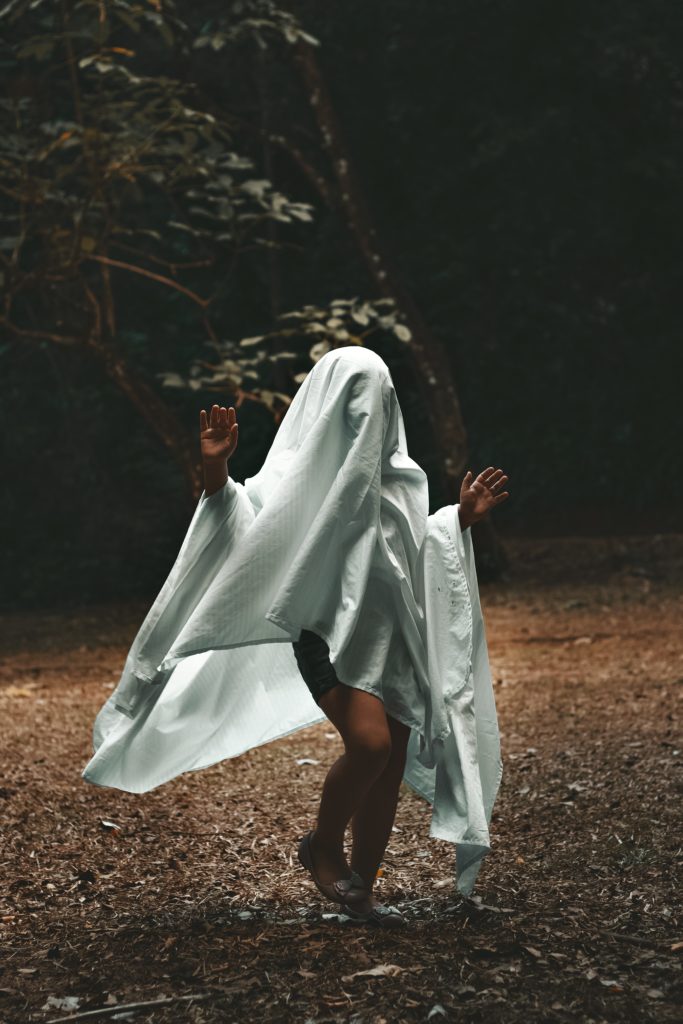 Scary ghost girl wearing a sheet in the woods.