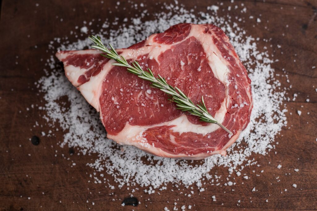 A seasoned ribeye steak with salt and rosemary.