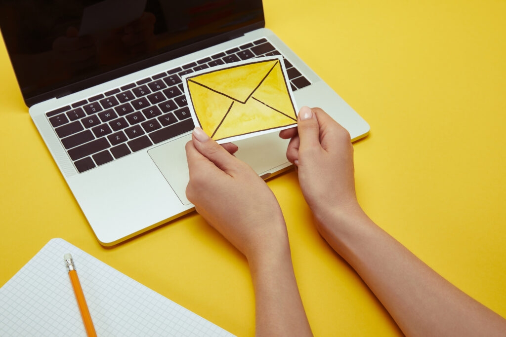 cropped image of woman holding envelope sign near laptop