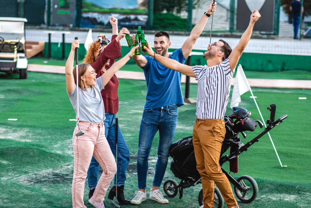 Group of smiling friends going to play mini golf in the city.